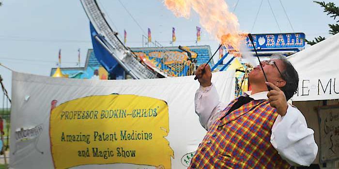 Eric Scites, a circus performer, breathes fire as a part of his medicine and magic show in Heritage Village at the Madison County Fair.